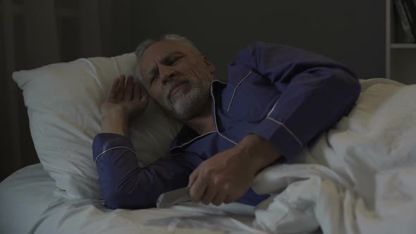 Annoyed Senior Man Suffering Insomnia and Nervously Switching Tv Channels