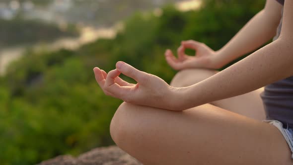 A Young Woman Meditates on a Mountain Over a Big City