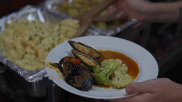 A close up shot of a plate. A woman taking delicious food in buffet