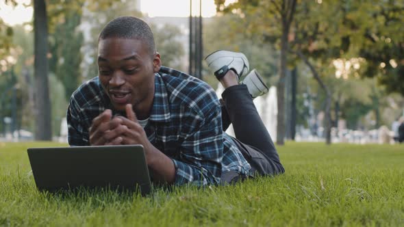 Male Student African American Guy Business Man Freelancer Lies on Green Grass Lawn in Park with