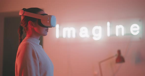 Profile view of a young woman wearing vr goggles with imagine sign in the background