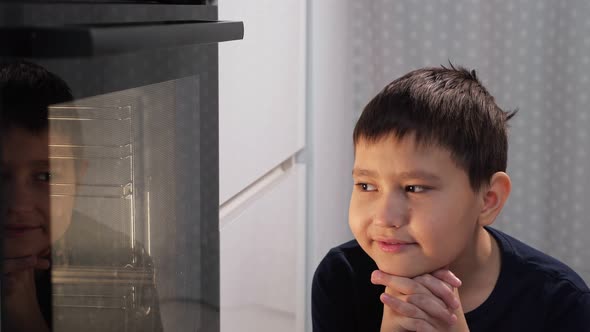 Boy Sits and Looks at the Oven While Waiting for the Dish