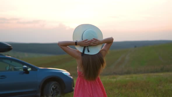 Young Woman Relaxing Alone on Green Field During Road Trip in Summer