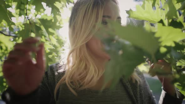 Happy Blond Girl at Sun Trees Foliage Closeup