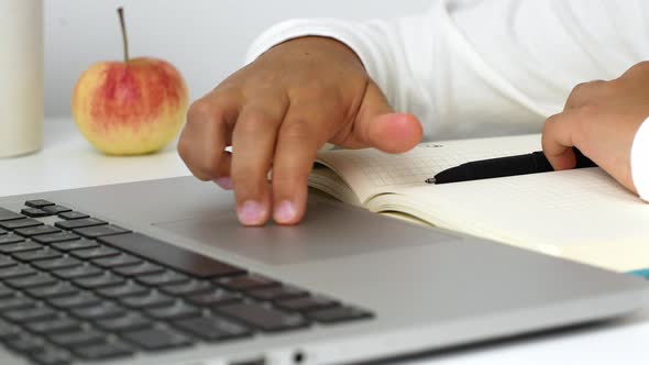 A child girl on distance learning sits in front of a laptop and does homework. Distance learning