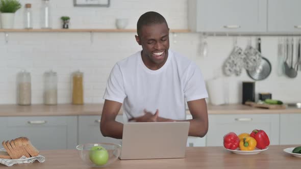 Sporty African Man Talking on Video Call on Laptop in Kitchen