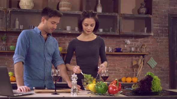 Wife Stirs the Salad Husband Stand Near