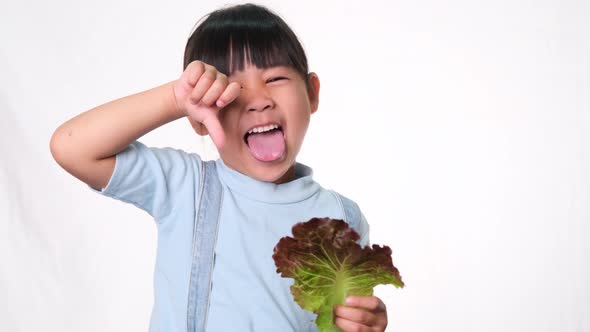 Children do not like to eat vegetables. Little girl who hates eating green salad.