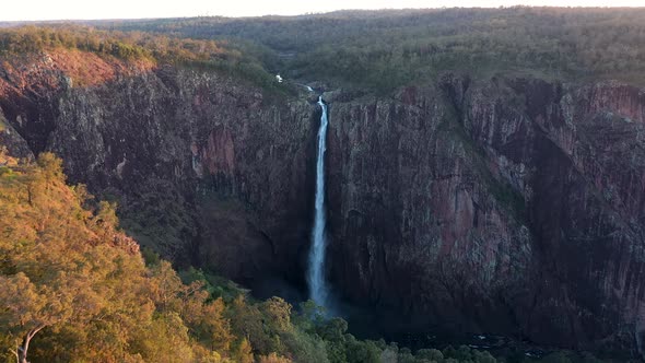 Wallaman Falls dusk aerial of breathtaking waterfall and golden sunlight on trees, Queensland