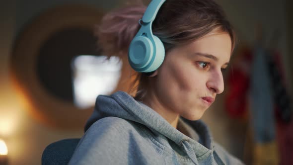 Happy woman in headphones typing by laptop