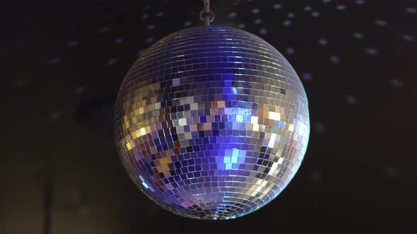 A Rotating and Sparkling Disco Ball on the Ceiling in a Dark Room