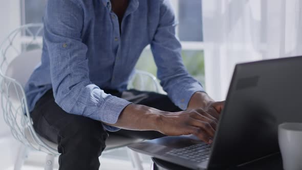 Unrecognizable African American Man Typing on Laptop Keyboard in the Morning in Home Office