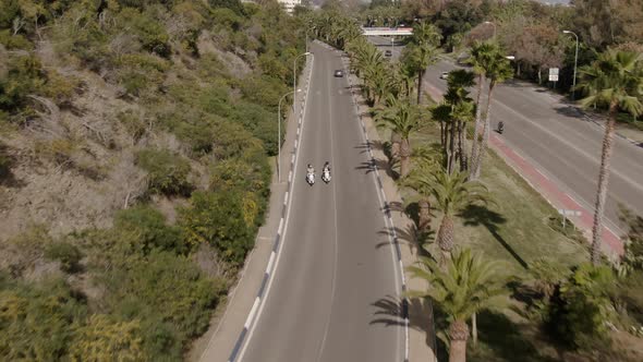 Rising drone shot of two people riding motorbike in Marbella Spain