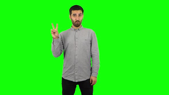 Brunette Guy Is Showing Two Fingers Victory Gesture. Green Screen