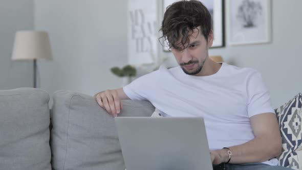 Young Man Working On Laptop While Relaxing on Couch