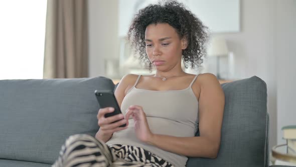 Serious African Woman Using Smartphone at Home