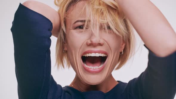 Stressed Caucasian Middleaged Blonde Female Screaming on White Background Mixing Hair in Despair