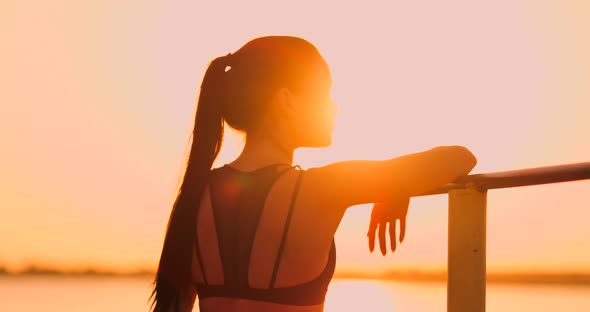 Woman Resting While Standing in the Sunset Bar Near the Rear View