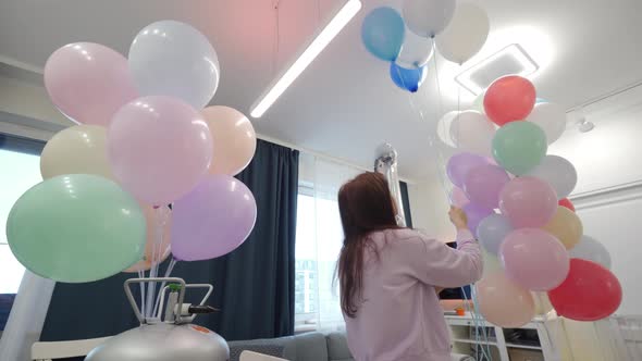 Woman Using Helium Tank Blowing Up Balloons to Decorate Home for Party Colorful Balloons for