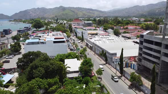 Aerial drone rising over the busy capital city with traffic, buildings and landscape in Dili, Timor