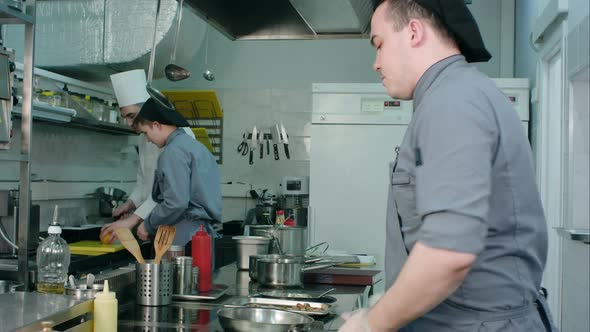 Chef Showing Young Trainee How To Slice Orange