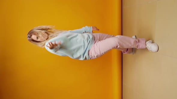 Vertical Video of a Woman Dancer Moving Against Yellow Background in Studio