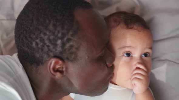 Happy African Father Lying on Bed with Newborn Baby