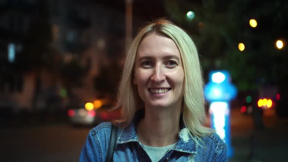 Portrait of a beautiful stylish blonde smiling at the camera. night city