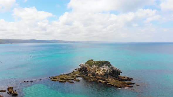 Aerial shot of birds flying over islands on the blue ocean waters of southern Victoria.