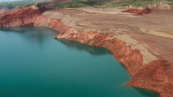 A Drone Flying Over a River with Water and a Sand Quarry on the Background of a Green Valley with