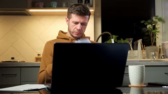 Man Works Using Laptop at Home Workplace Reading Paper Documents