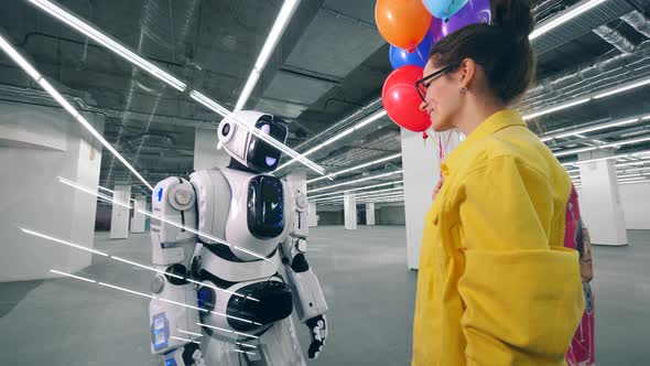 Smiling Lady Is Giving Colourful Balloons To a Robot