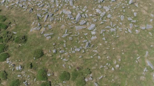 Birdseye aerial tracking backwards over rocks in a moorland setting. Dartmoor, England.