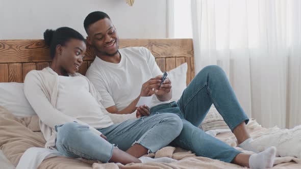 Happy Future Parents African Married Couple Lie Sitting on Sofa Watching Pictures Ultrasound Film