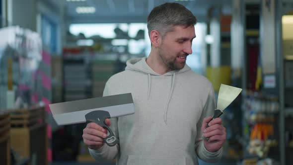 Bearded Caucasian Man Choosing Putty Knife in Hardware Store