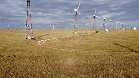 An Aerial View of a Drone Flying Near White Wind Turbines at Medium Altitude Standing in a Steppe