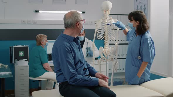 Female Specialist Pointing at Spinal Cord on Human Skeleton