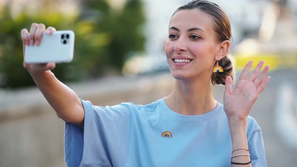 A positive lovely woman with rainbow make-up taking selfie photo using her phone during pride gay pa