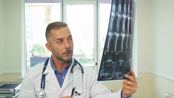 A Thoughtful Doctor Carefully Examines an X-Ray Shot