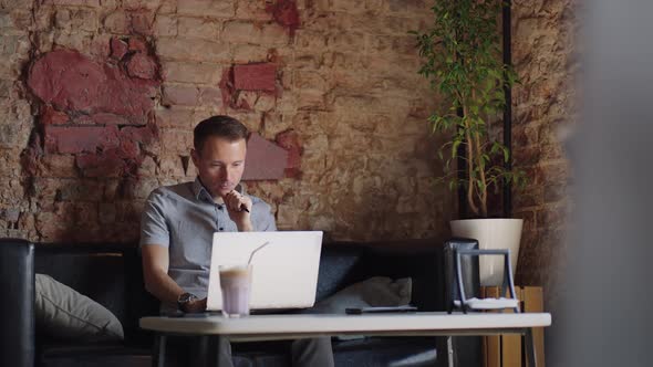 Thoughtful Serious Young Man Student Writer Sit at Home Office Desk with Laptop Thinking of