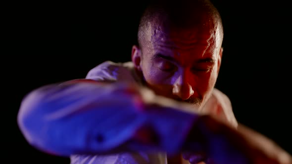 a Man in an Unbuttoned White Shirt is Boxing on a Dark Background