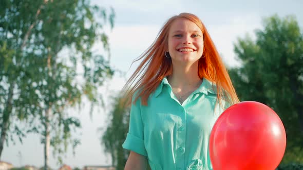 Beauty girl with red hair and colorful air balloons spinning and laughing, on white background. Beau
