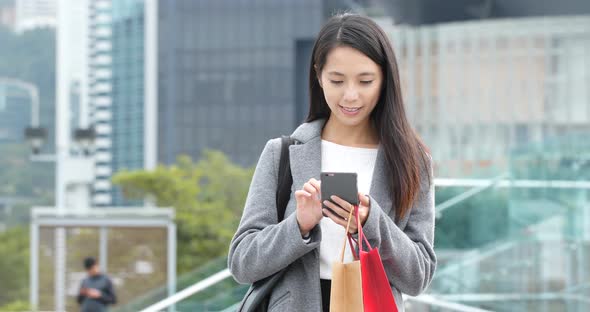 Woman use of smart phone and holding shopping bag