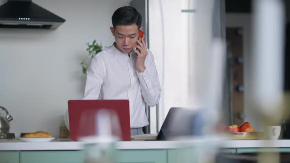 Portrait of Cheerful Chinese Man Rejoicing Business Idea Talking on the Phone Typing on Keyboard