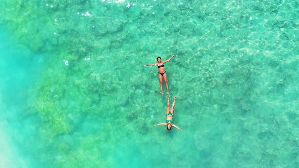 Pretty smiling girls relaxing by the sea at the beach on summer white sandy and blue background 4K