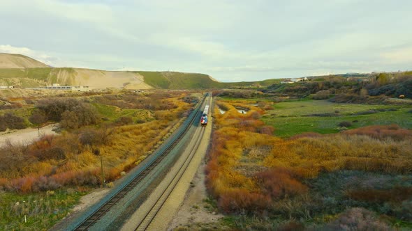 AERIAL - Train on railroad tracks next to mesas, Bluffdale, Utah, tracking shot