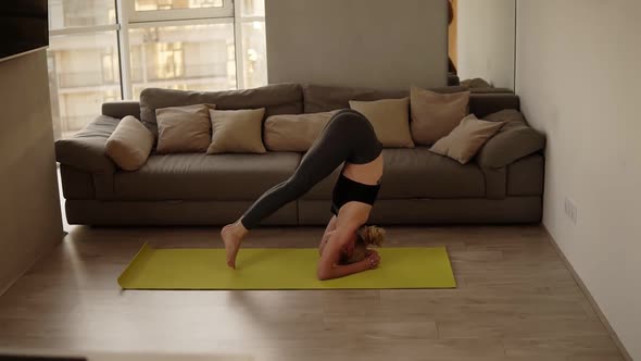 Blonde Sexy Slim Fit Woman Performing Correct Head Stand Asana and Gently Raises Legs and Come Back