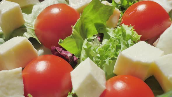 Pour Olive Oil on Italian Salad with Mini Mozzarella Tomatoes Cherry and Arugula Rotating