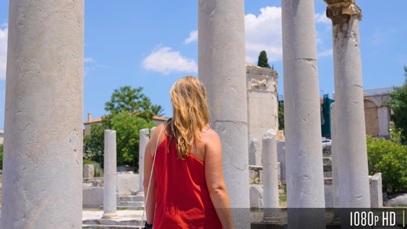 Woman Walking in Slow Motion Next to Ancient Greek Columns in the Roman Forum of Athens, Greece