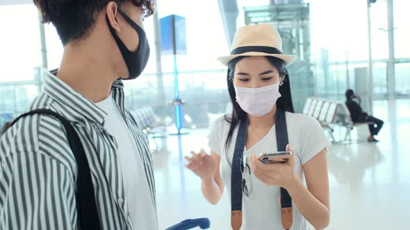 Asian male and female wearing protective face mask in airport terminal